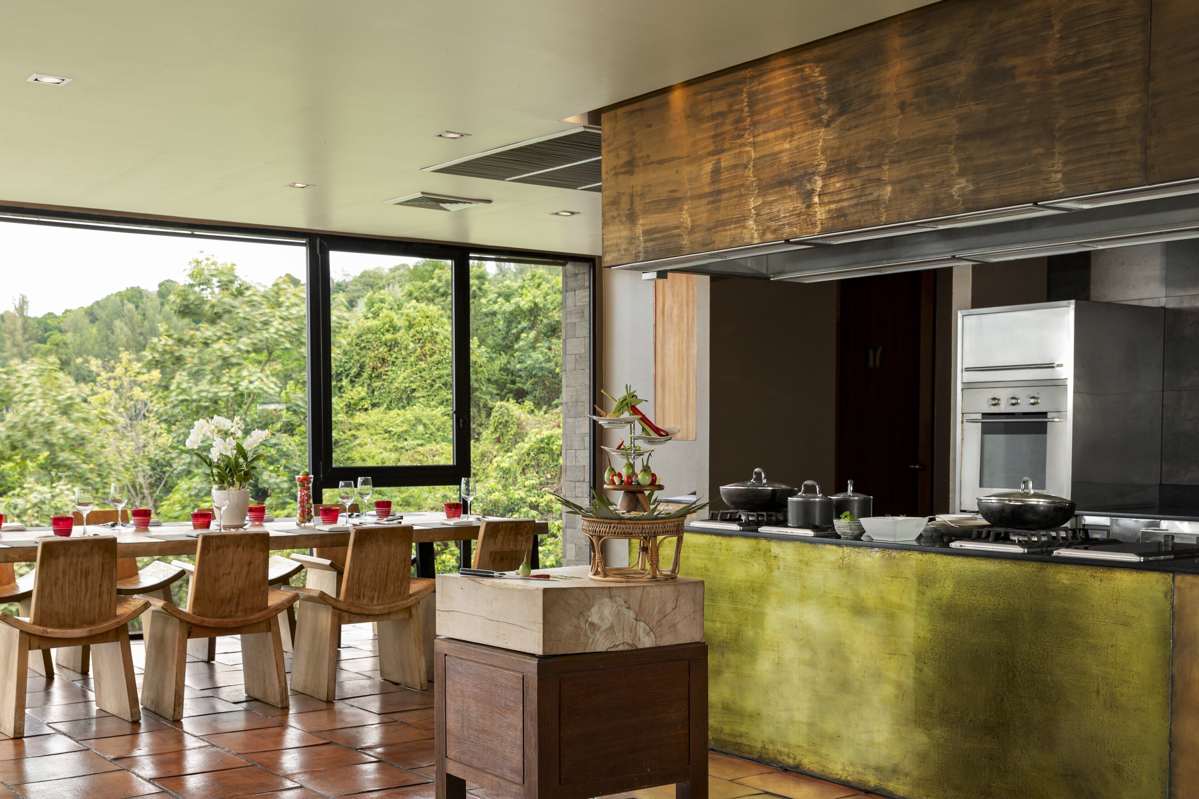 Una cocina moderna con una isla grande, electrodomésticos de acero inoxidable y un comedor con sillas de madera y una mesa dispuesta para cuatro.