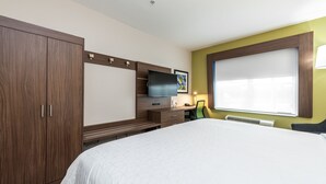 Une chambre d’hôtel avec un grand lit, une télévision, un bureau et une armoire.