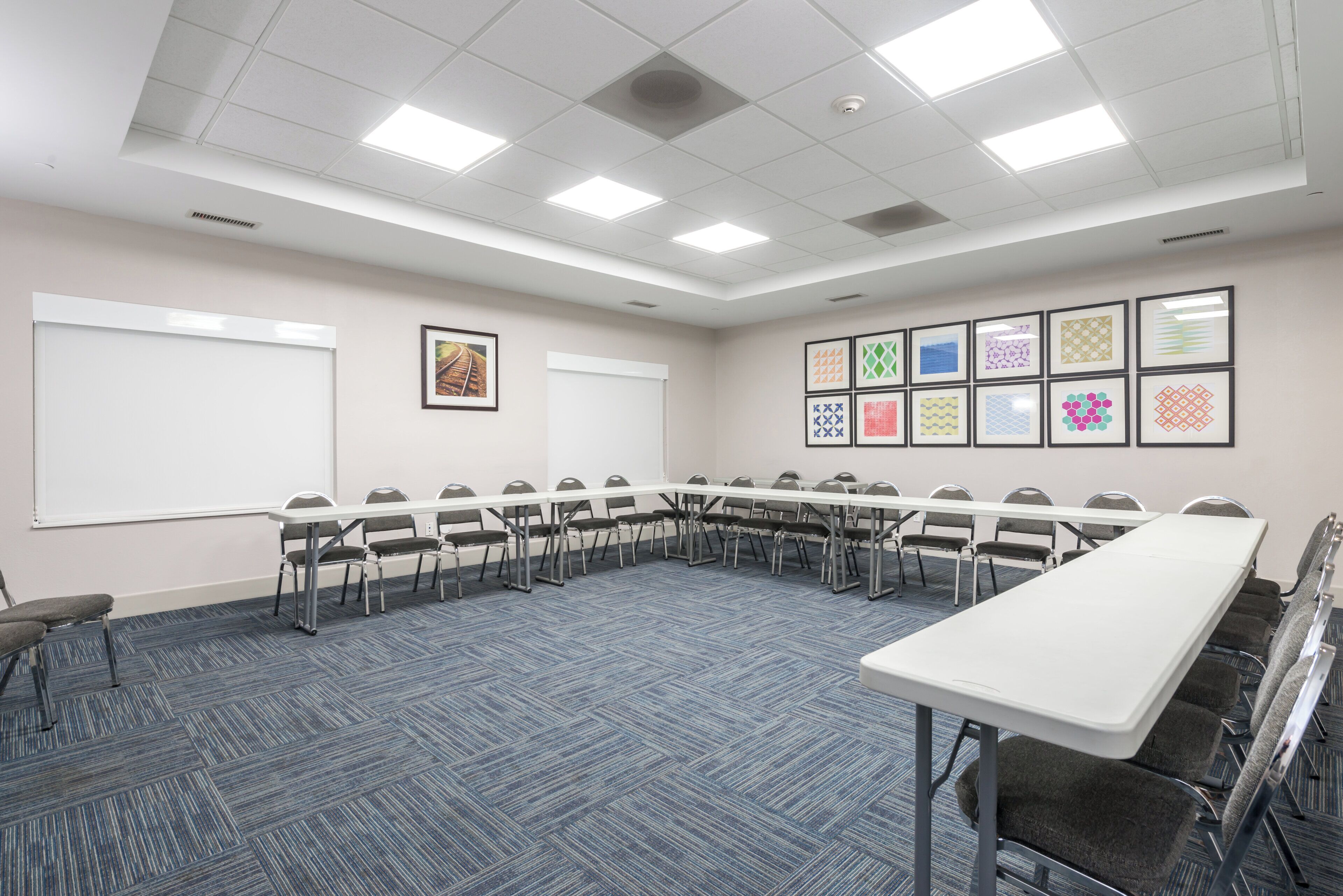 A conference room with a long table, chairs, a whiteboard, and framed pictures on the wall.