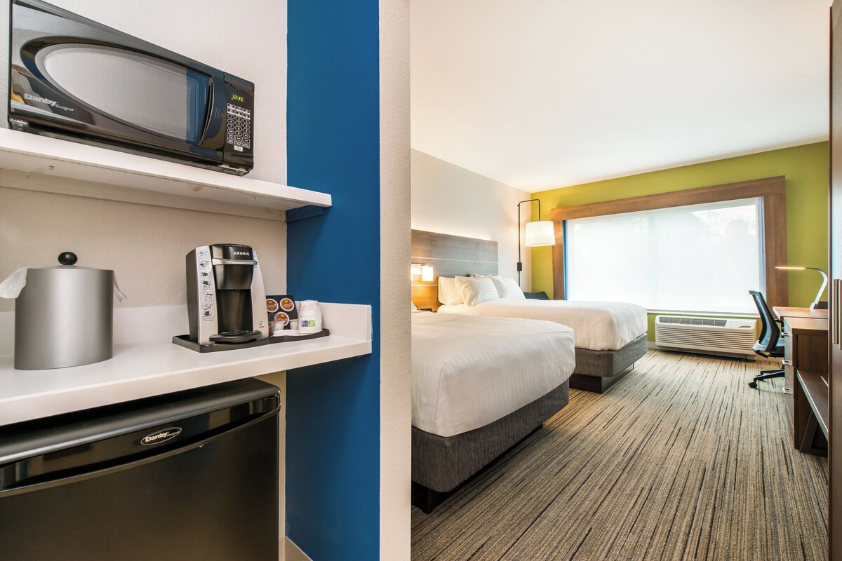 A hotel room with a microwave, coffee maker, and a minibar.
