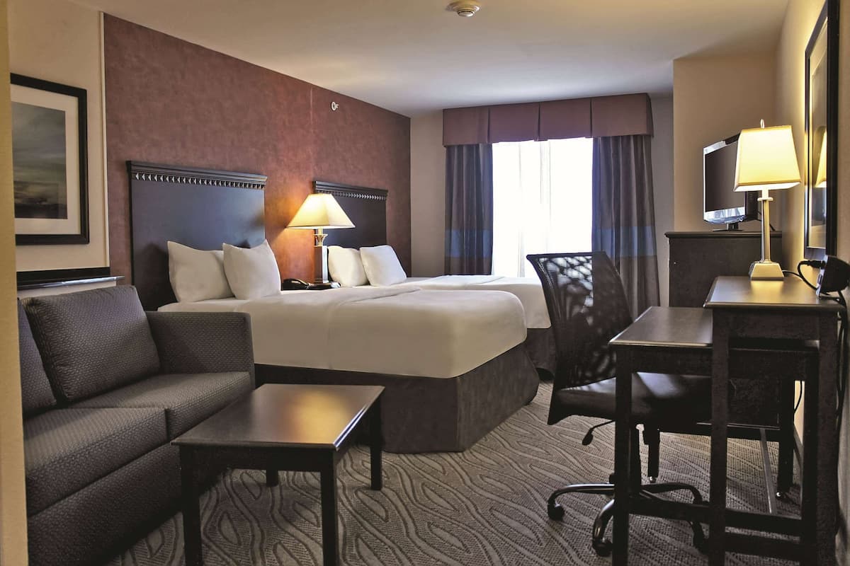 Een hotelkamer met een groot bed, een bank, een bureau, een stoel en een televisie.