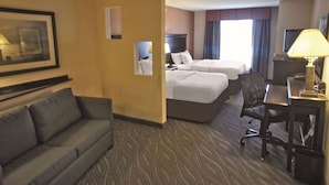 Une chambre d’hôtel avec deux lits, un canapé, un bureau et une télévision.