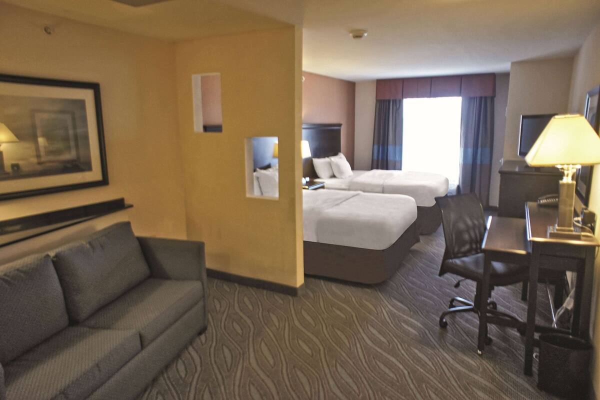 Een hotelkamer met twee bedden, een bank, een bureau en een televisie.