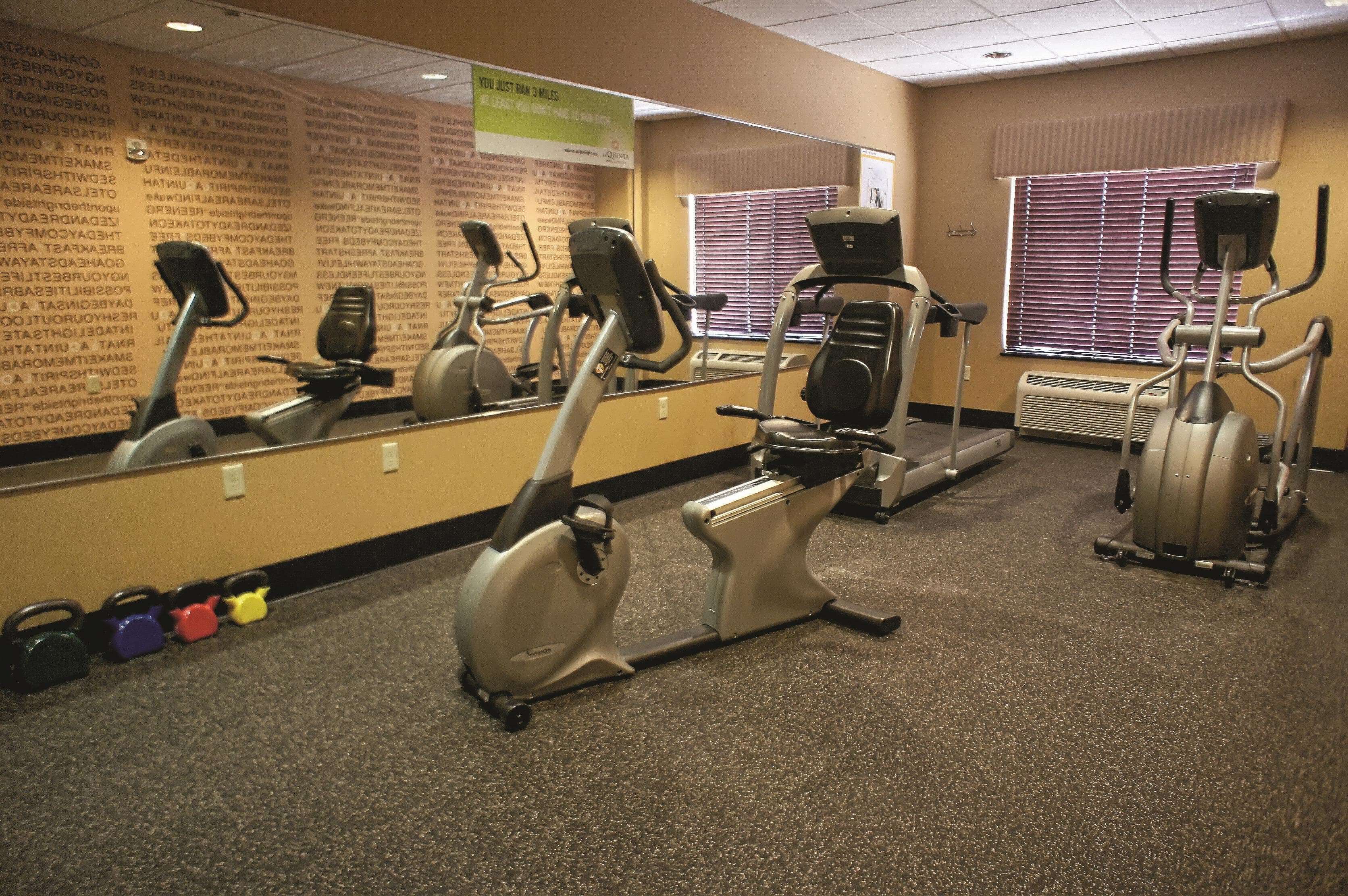 A gym with exercise equipment, a mirror, and a wall with motivational quotes.