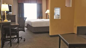 A hotel room with a bed, desk, chair, and a small table.