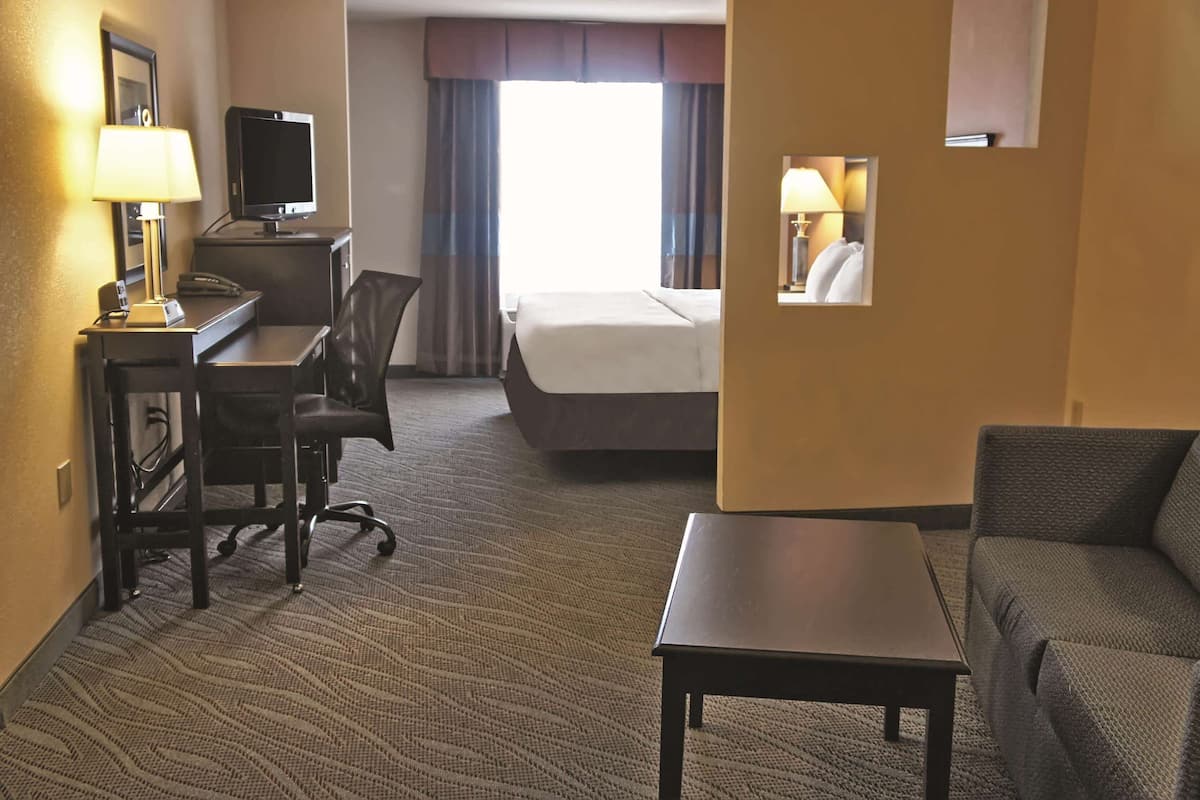 Een hotelkamer met een bed, een bureau met lamp, een televisie, een stoel en een bank.