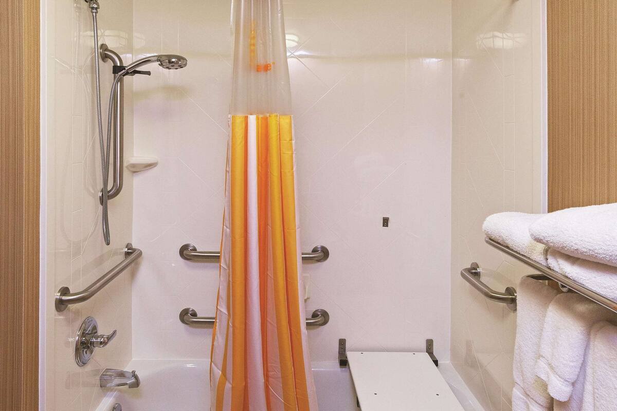 Een moderne badkamer met een inloopdouche, handgrepen, een badkuip en een handdoekrek.