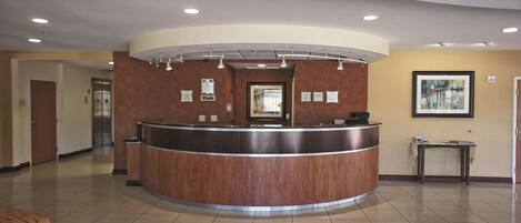 A reception area with a curved counter, a framed picture on the wall, and a small table with a tablecloth.