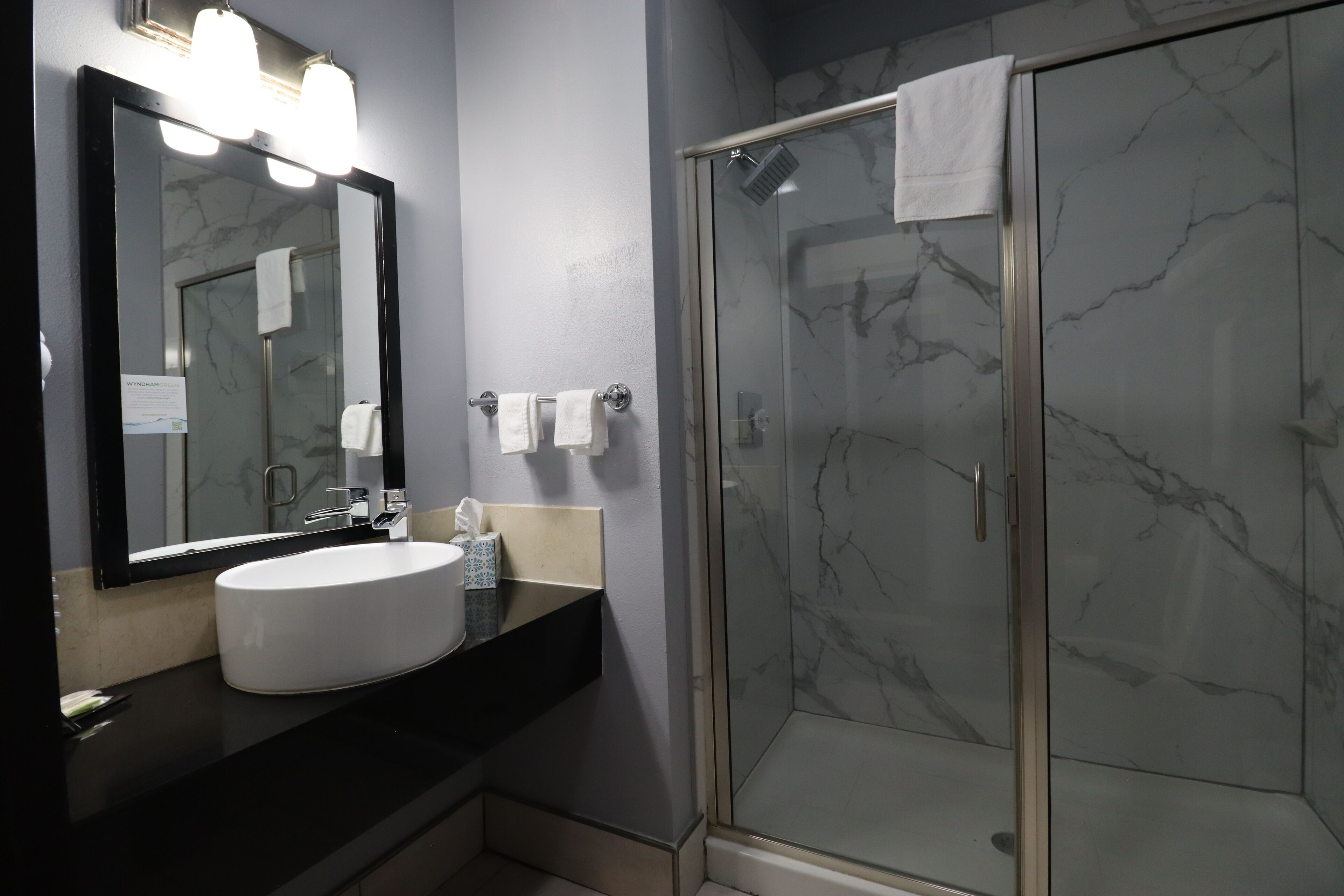 A bathroom with a white sink, a large mirror, and a glass shower enclosure.