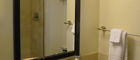 Un baño con un espejo grande, un lavamanos tipo cuenco y un perchero para toallas.