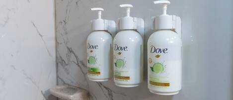 Three Dove body lotion bottles mounted on a marble wall.