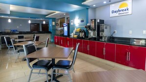 Un restaurante con decoración roja y negra, un letrero que dice Daybreak Breakfast y una barra con cafeteras.