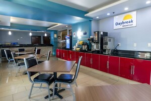 Un restaurante con decoración roja y negra, un letrero que dice Daybreak Breakfast y una barra con cafeteras.