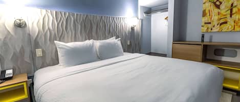 Una habitación de hotel moderna con una cama grande, una mesita de noche con teléfono, aire acondicionado instalado en la pared y un cuadro.