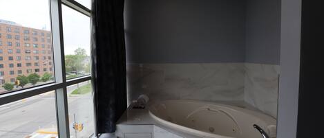 A modern bathroom with a large bathtub, a window with a view of a cityscape, and a towel rack.