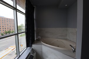 Un baño moderno con una bañera grande, una ventana con vistas a un paisaje urbano y un perchero para toallas.