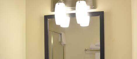 A bathroom with a large mirror, a sink with a marble bowl, a hairdryer, and a towel rack.