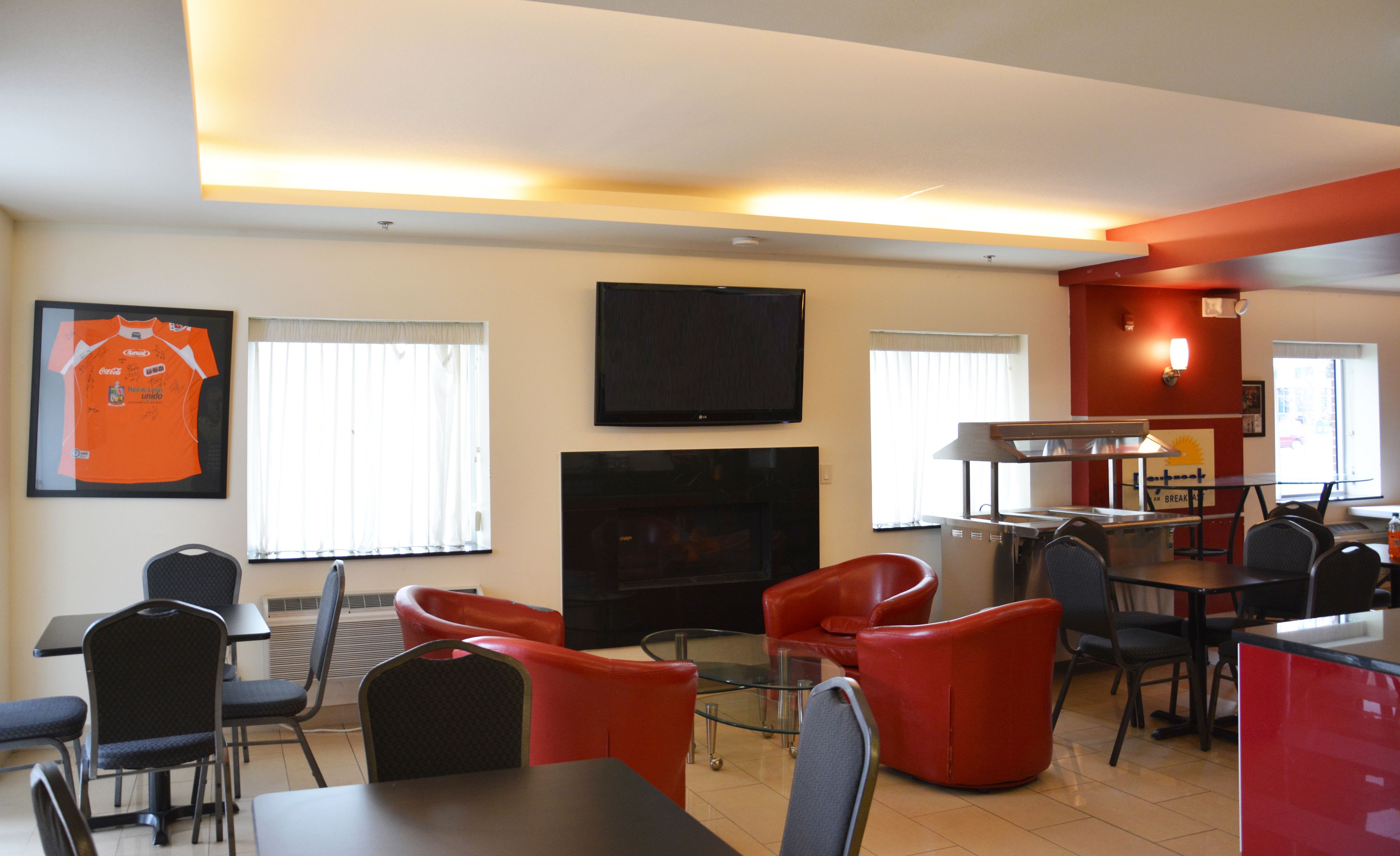 A dining area with red chairs, a TV mounted on the wall, and a sports jersey on the wall.