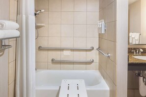 Un baño moderno con bañera, barras de apoyo y lavamanos.