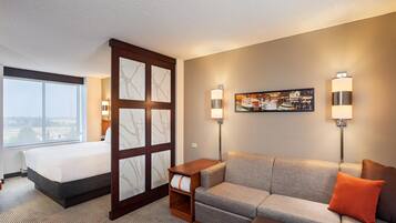 A hotel room with a bed, a sofa, a small table, and two wall-mounted lamps.