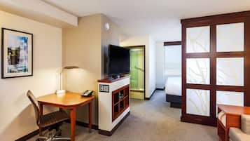 A hotel room with a desk, chair, television, and a bed.