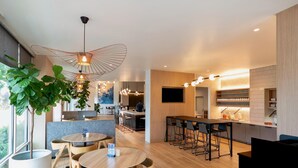 Un intérieur moderne avec des tables rondes, un bar et un espace cuisine.