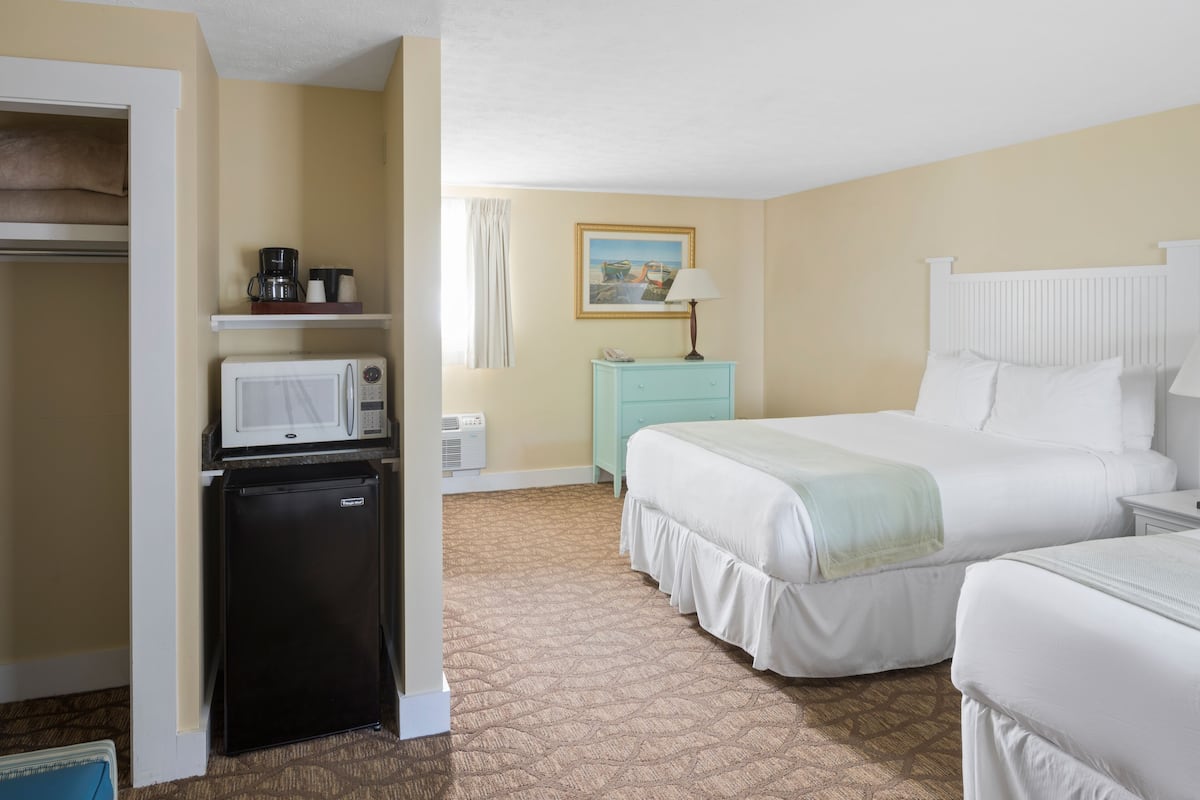 A hotel room with a bed, a desk, a microwave, a refrigerator, and a closet.