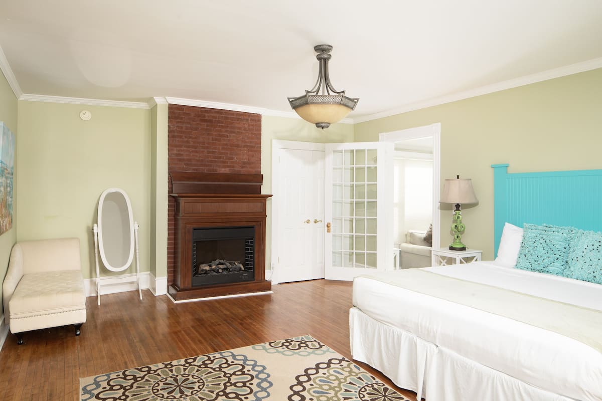 A bedroom with a fireplace, a bed, a chair, and a rug.