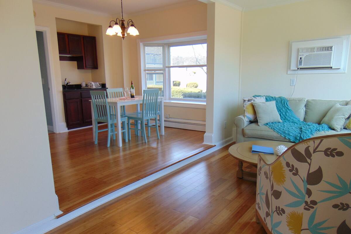 A living room with a sofa, a coffee table, and a dining area with a table and chairs.