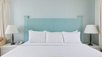 Una cama bien hecha con sábanas blancas, un cabecero azul claro y dos lámparas de noche.
