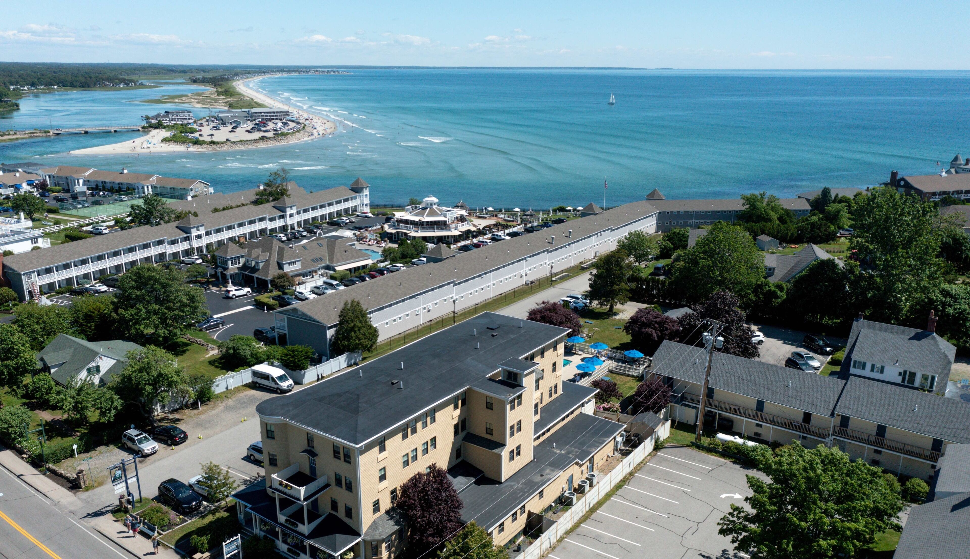 An aerial view of a coastal area with a large hotel building, a beach, and a marina.