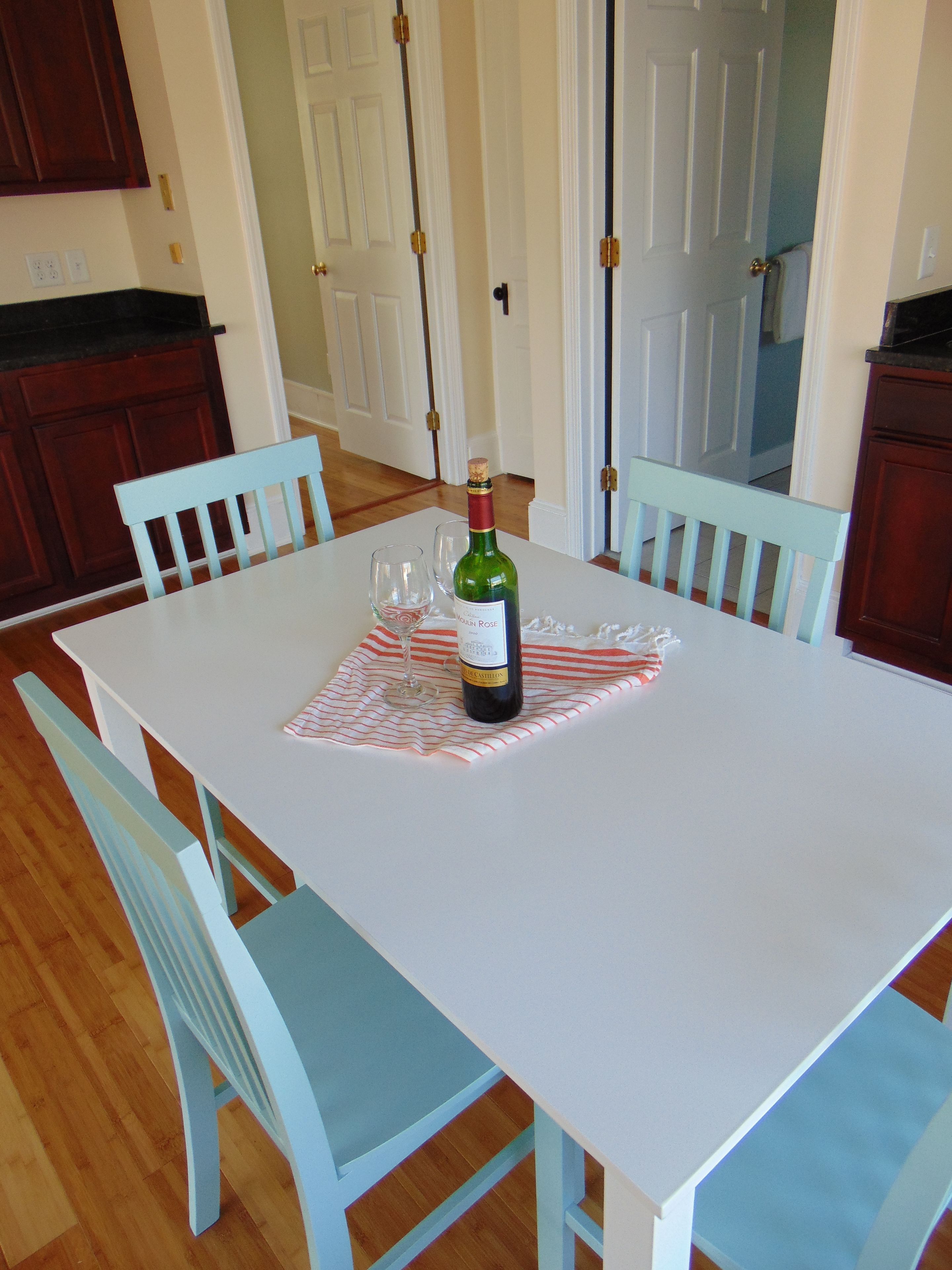 A dining table with a wine bottle and glasses, surrounded by light blue chairs.