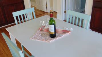 A dining table with a wine bottle and glasses, surrounded by light blue chairs.