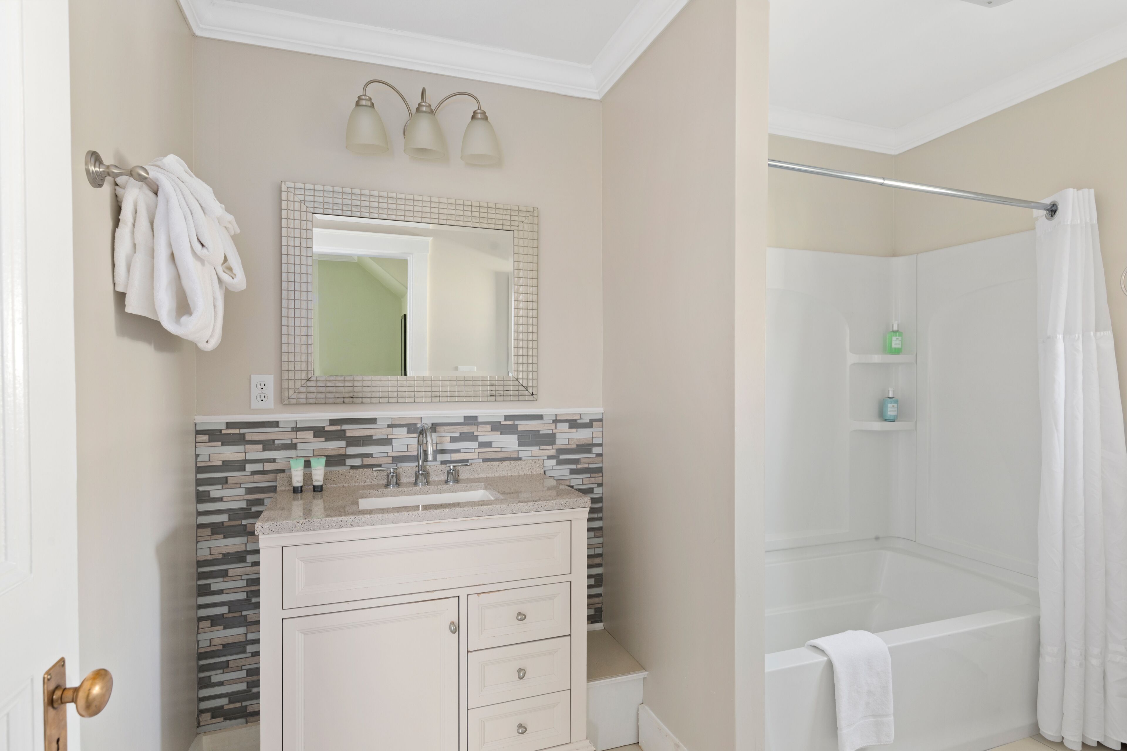 A bathroom with a tiled shower, a sink with a mirror, and a towel rack.
