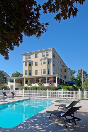 A multi-story hotel with a swimming pool, lounge chairs, and a white picket fence. - The Colonial Inn (Ogunquit)
