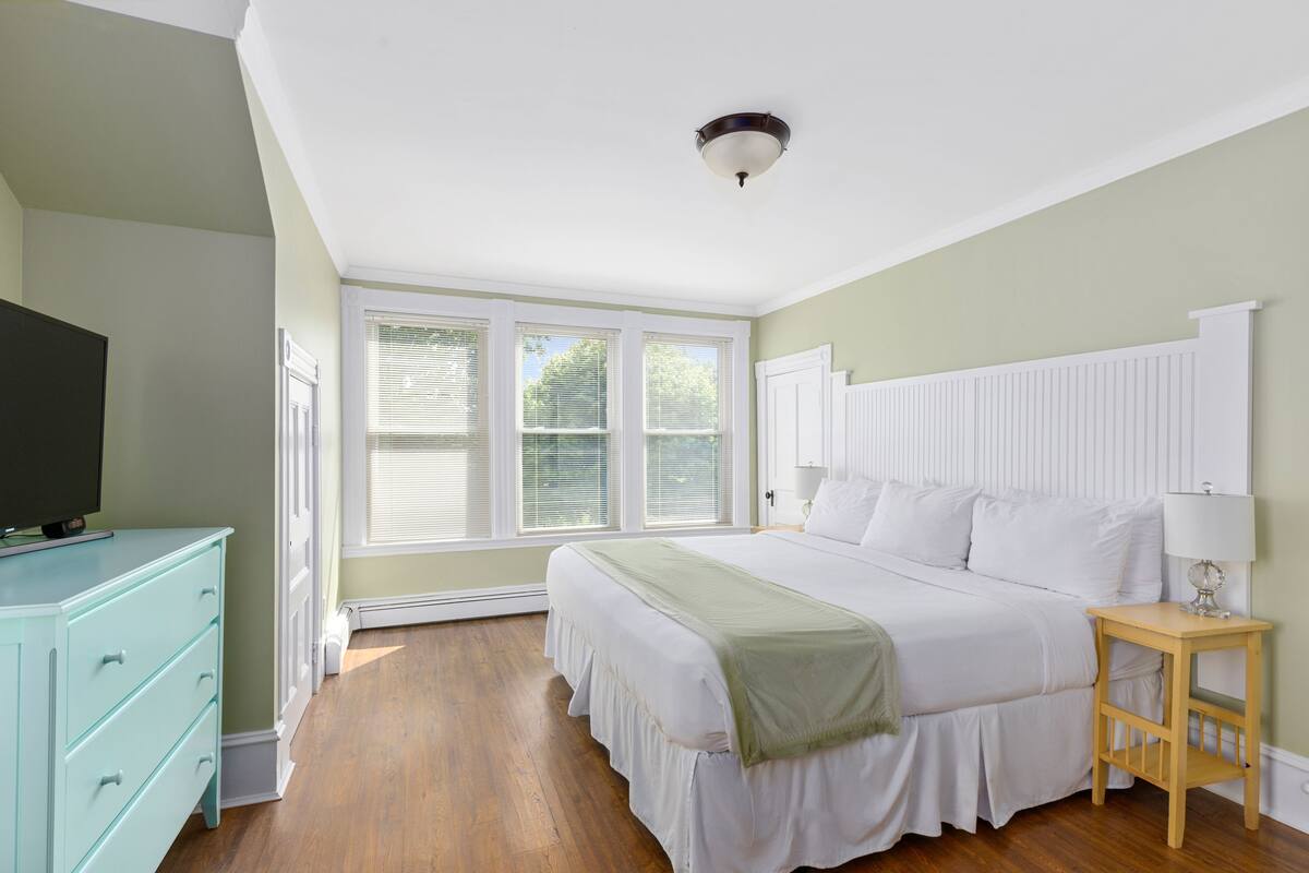 A bedroom with a bed, a dresser, a nightstand, and a television.