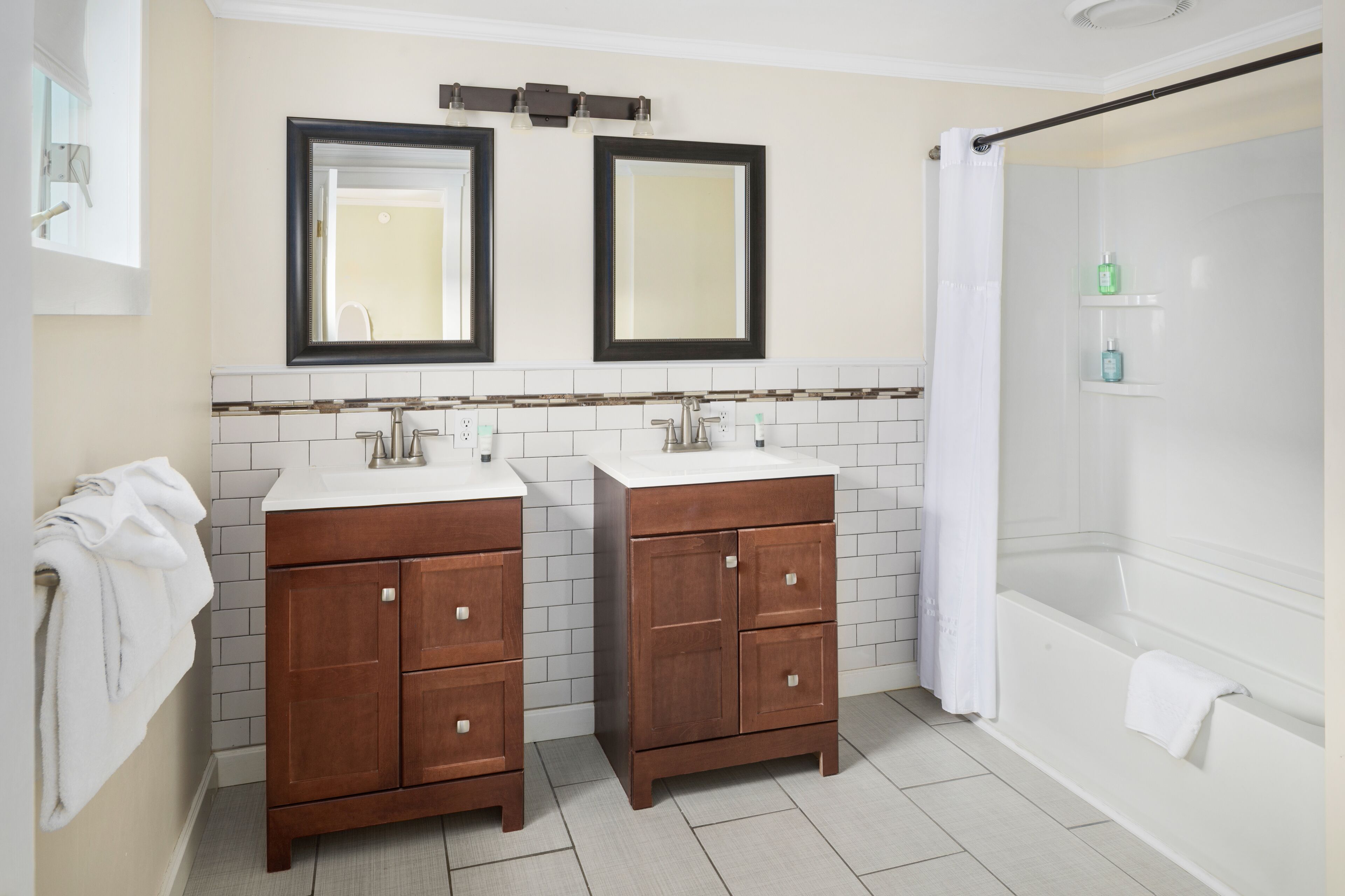 A bathroom with two wooden cabinets, a white bathtub, and a shower curtain.