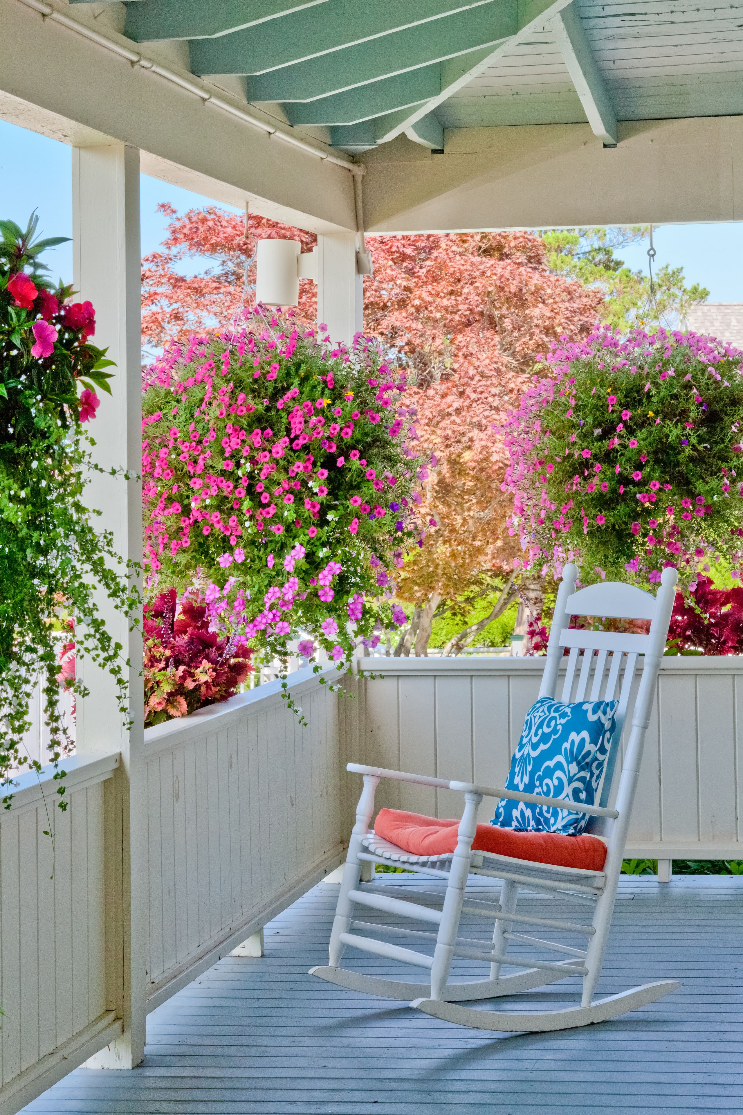 Una terraza de madera con una mecedora y barandilla blanca.