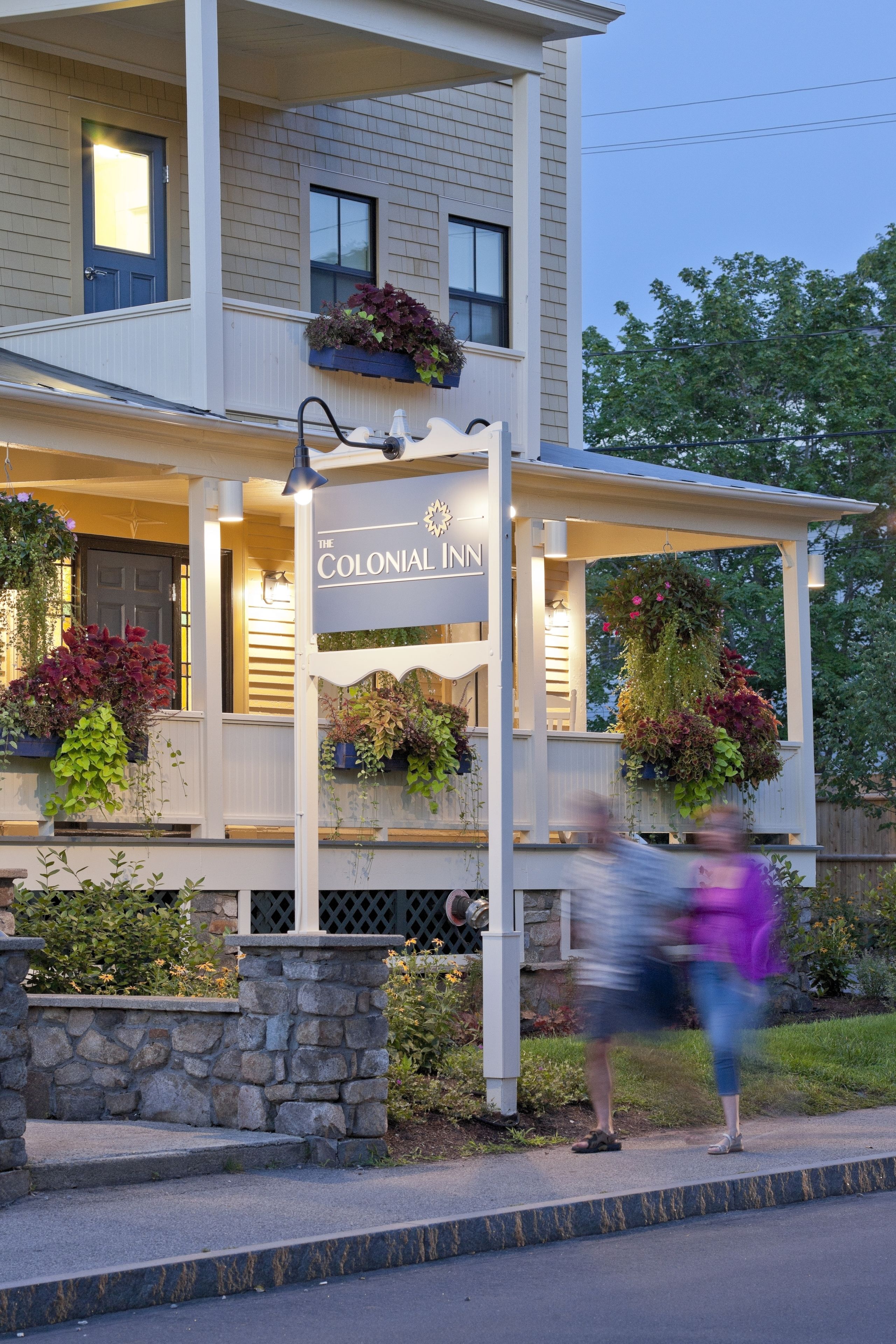 A building with a sign reading "The Colonial Inn" and a covered porch with potted plants.