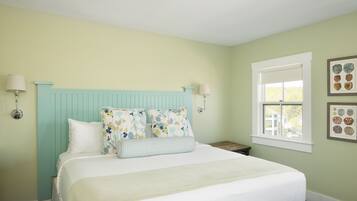A bedroom with a bed, two bedside tables, a window, and wall art.