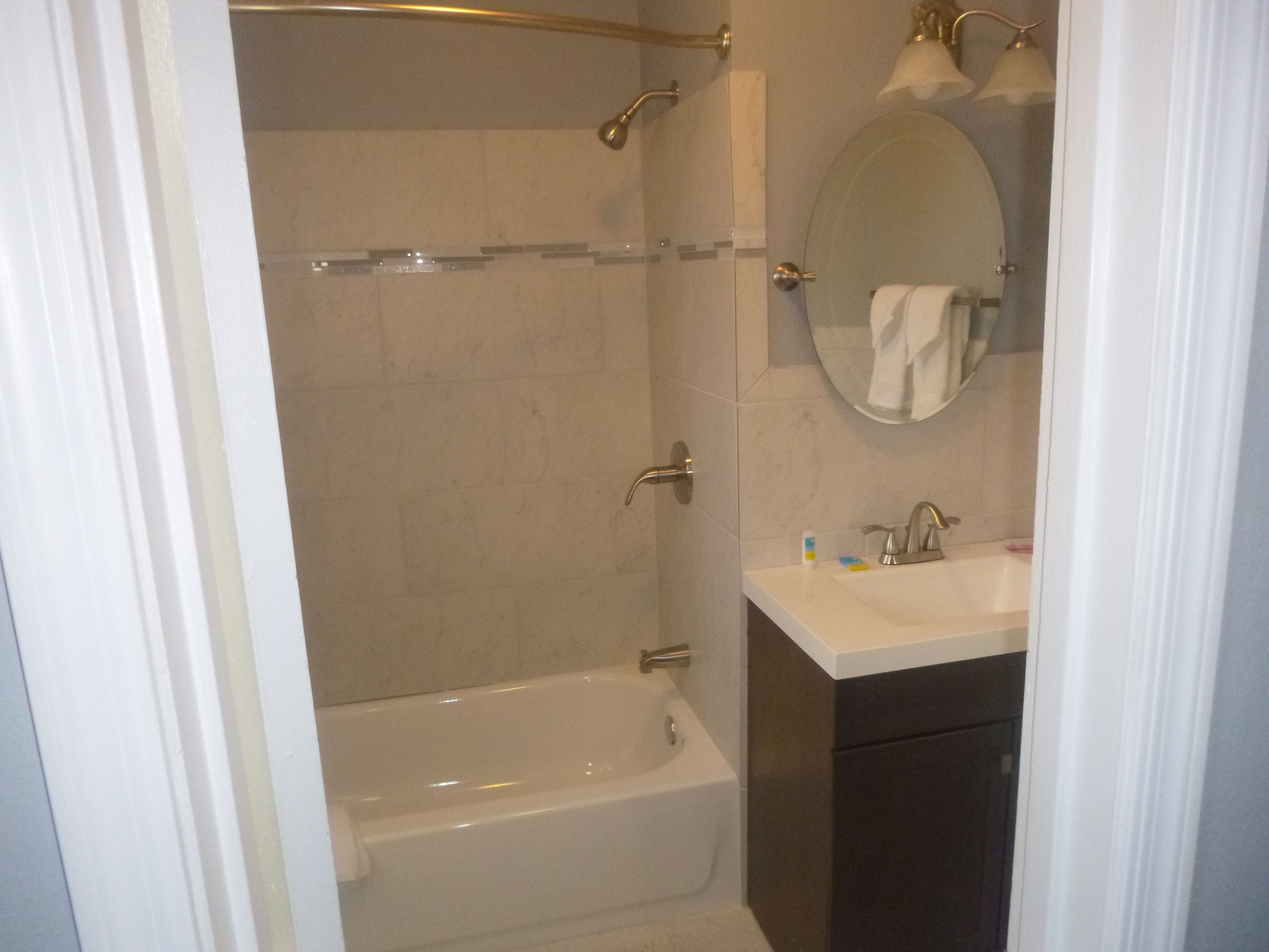 Een badkamer met een bad, een wastafel, een spiegel en een douche.