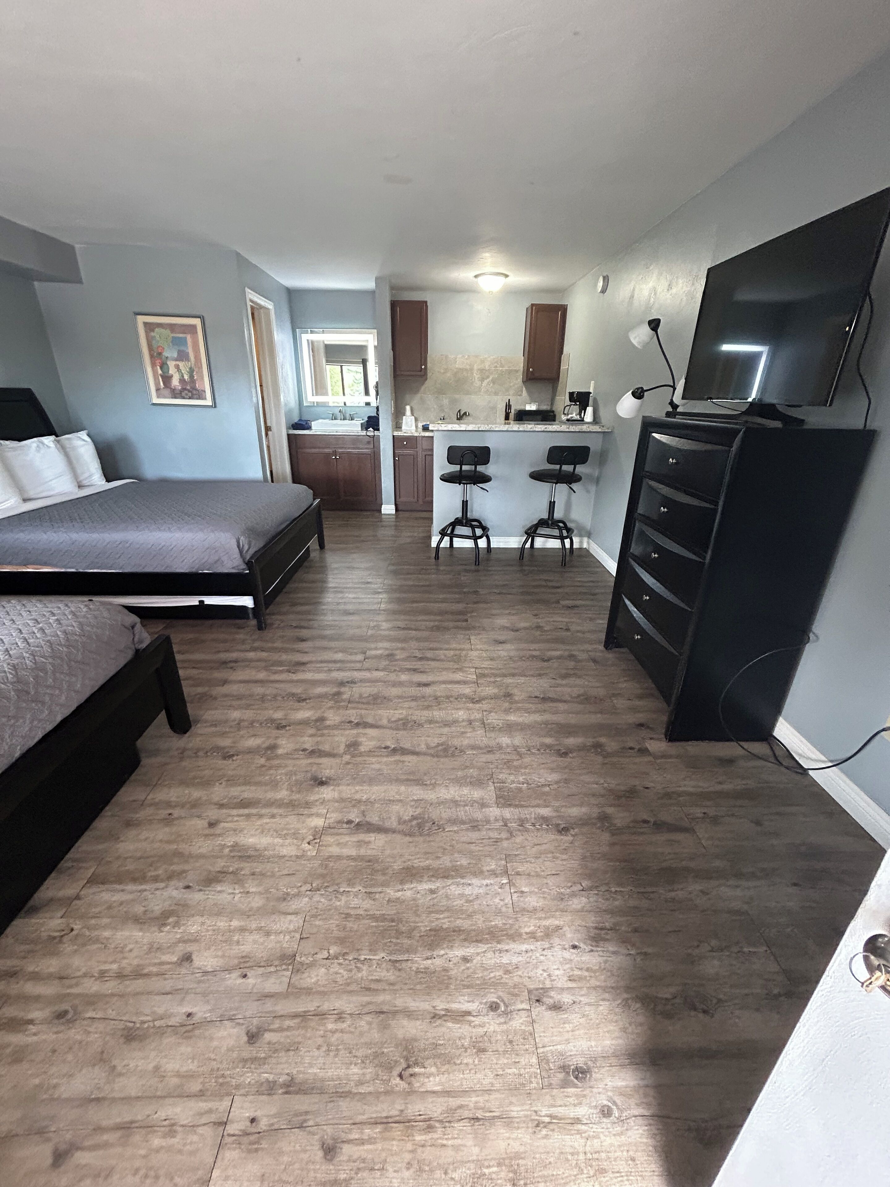 A compact studio apartment with a bed, kitchenette, and a TV.