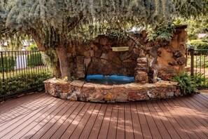 A stone fountain with a water feature, surrounded by a wooden deck and a stone wall. - Sierra Inn (Prescott)