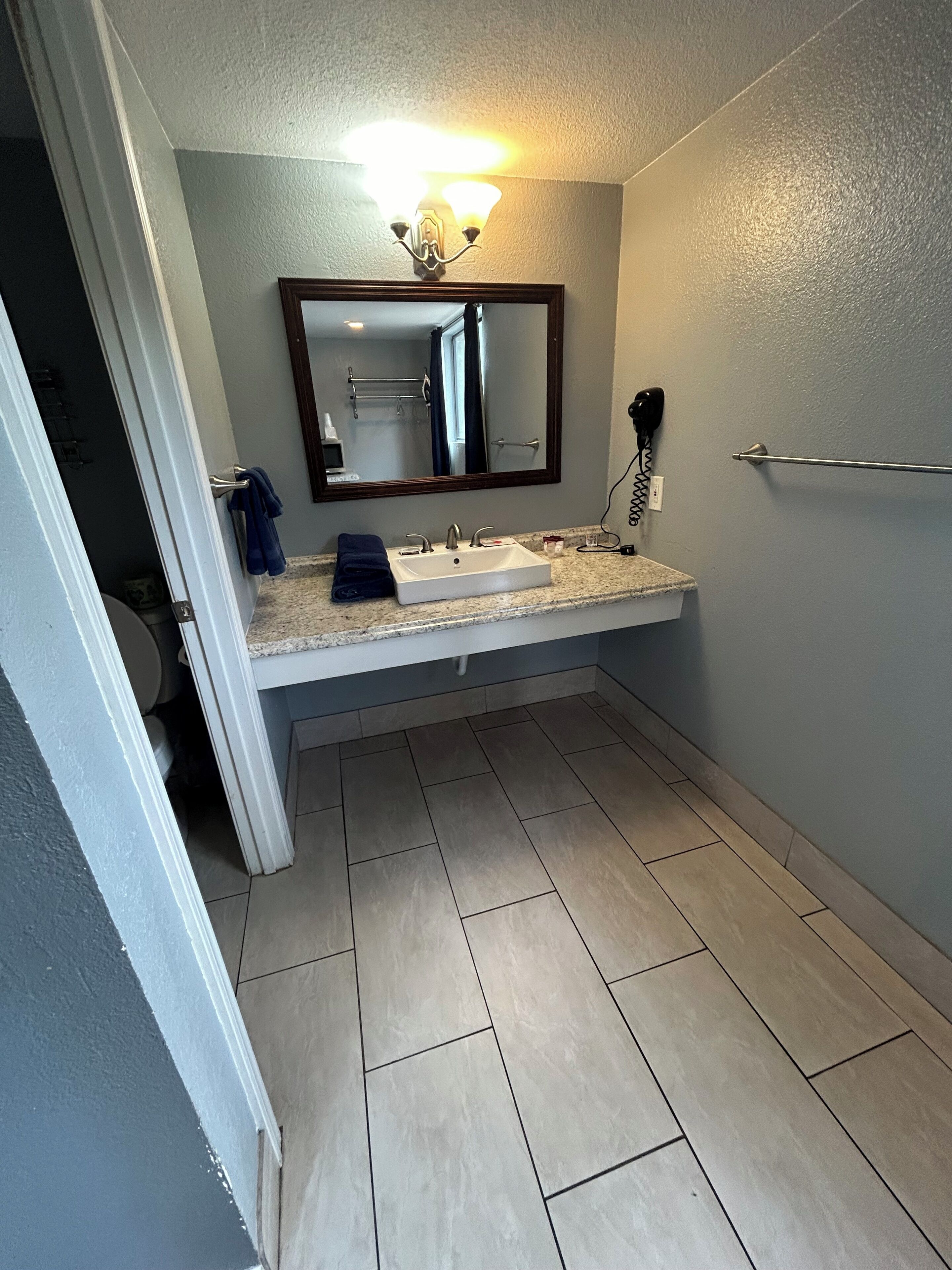 Une salle de bain avec un lavabo blanc, un miroir, un porte-serviettes et un rideau de douche.