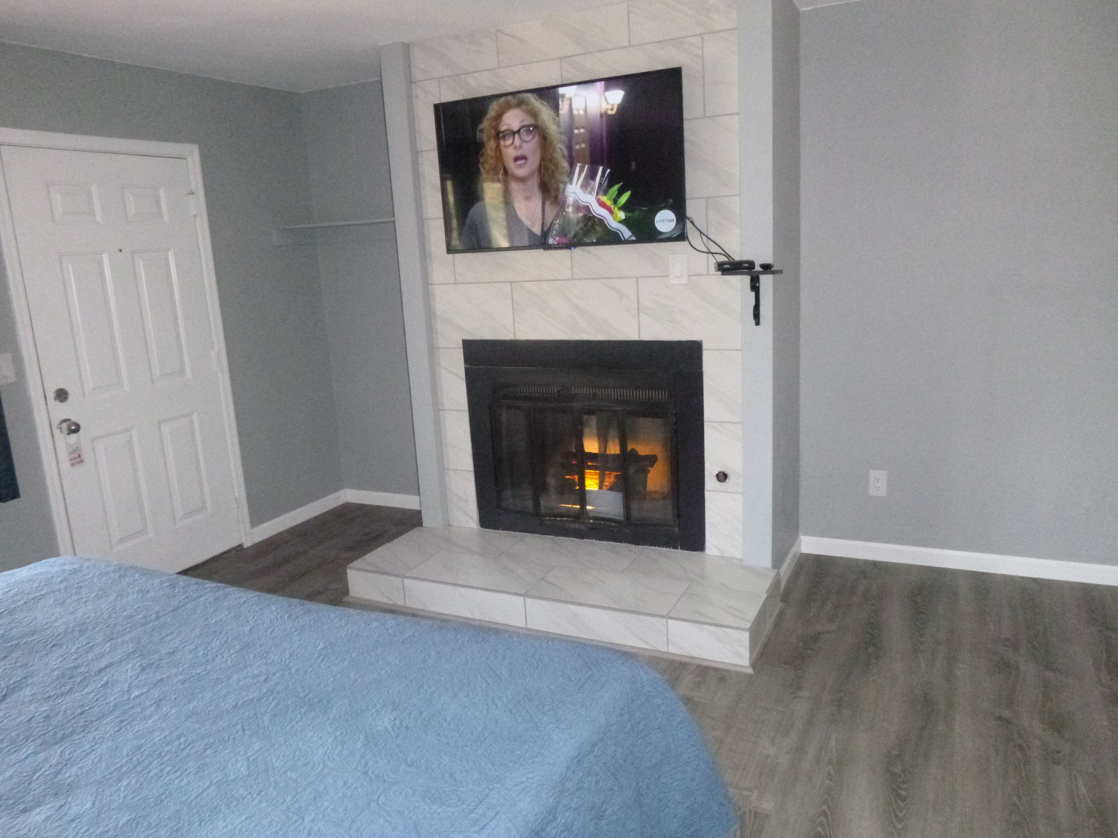 A living room with a fireplace, a television mounted above it, and a door to the left.