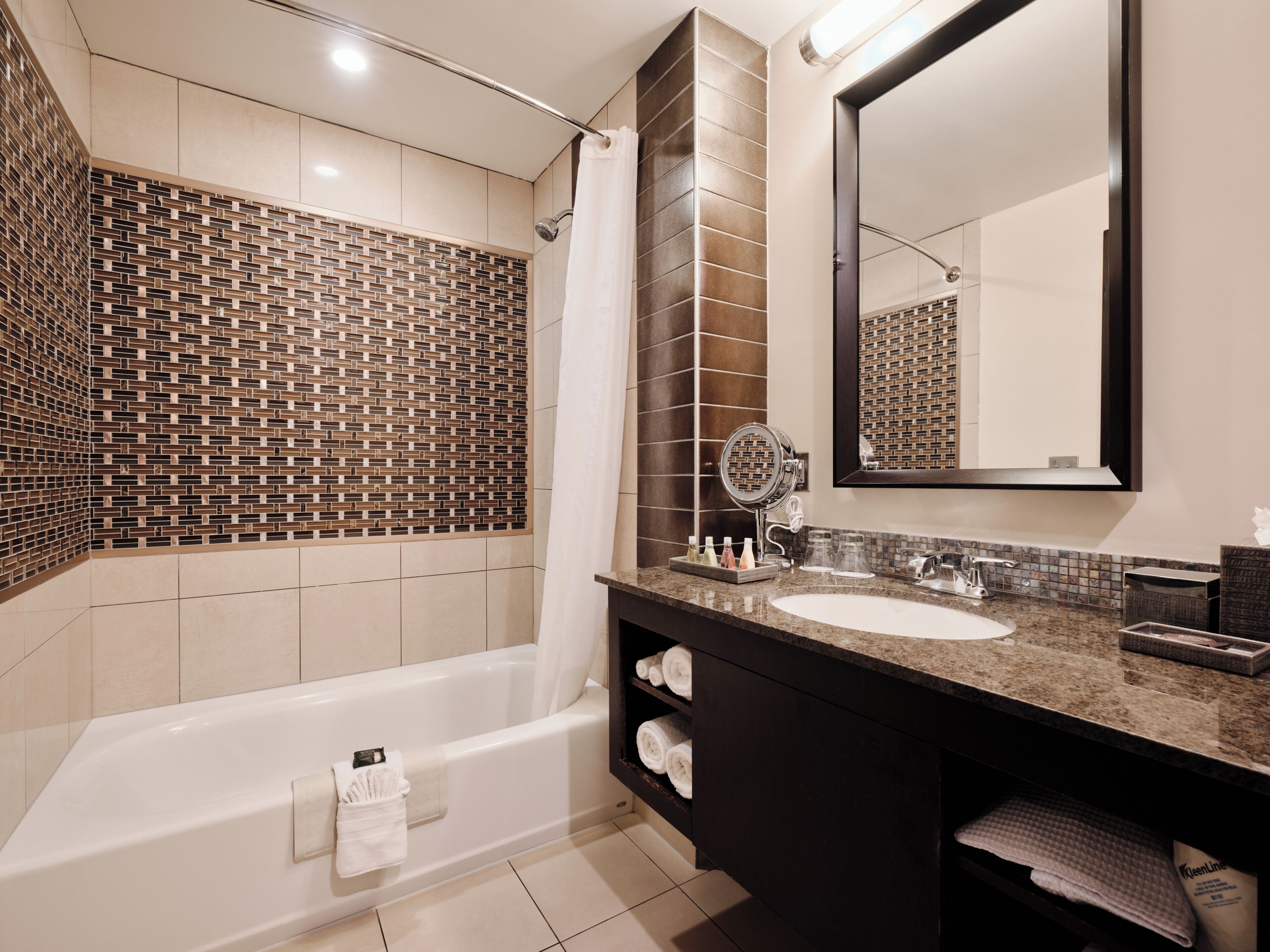 A modern bathroom with a large bathtub, a vanity with a mirror, and a tiled shower area.