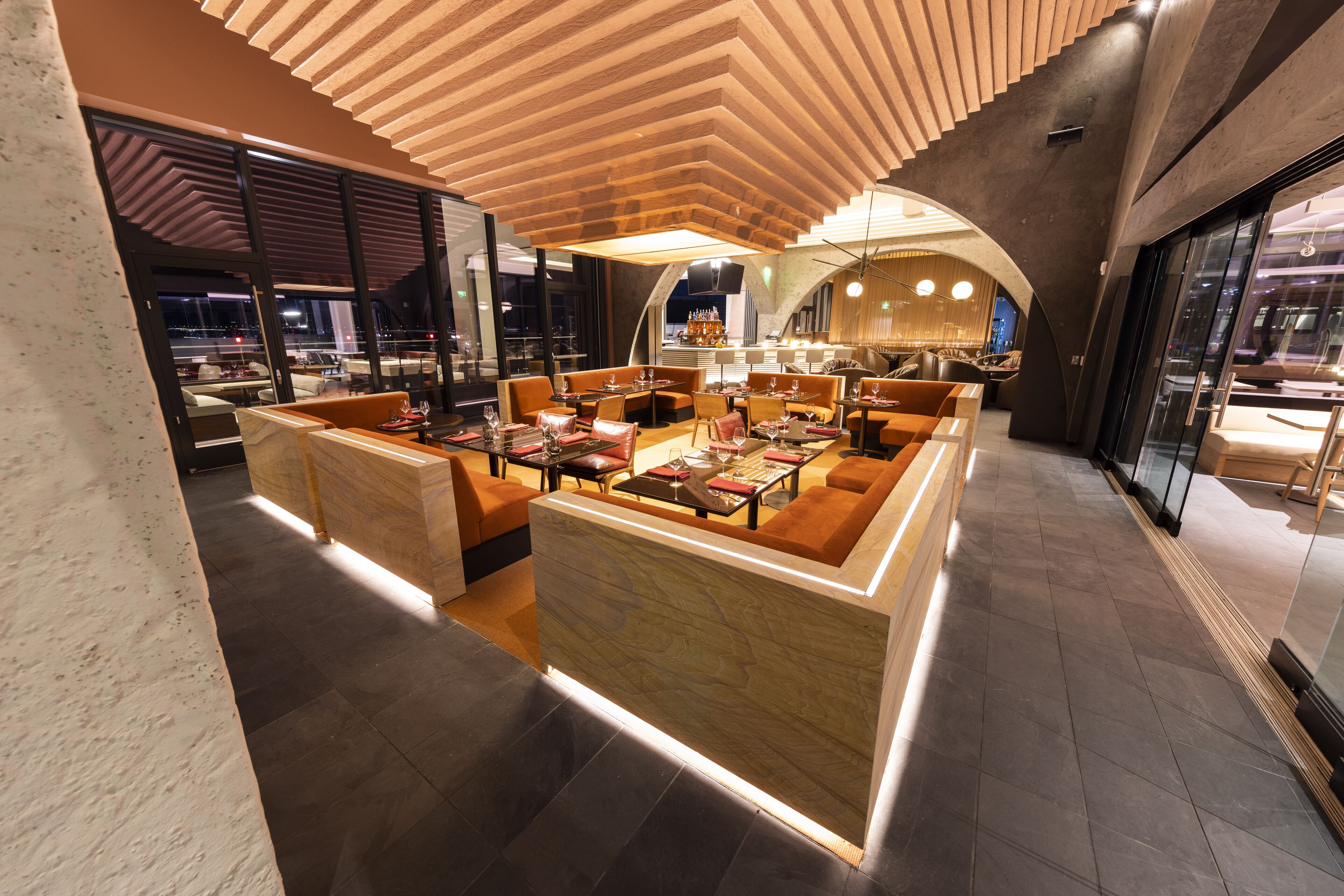 En modern inredning med en central sittgrupp, en bar och utsikt över stadsbilden genom stora fönster.