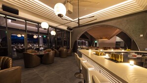Un espace bar moderne avec des sièges en cuir, un long comptoir et des luminaires suspendus.