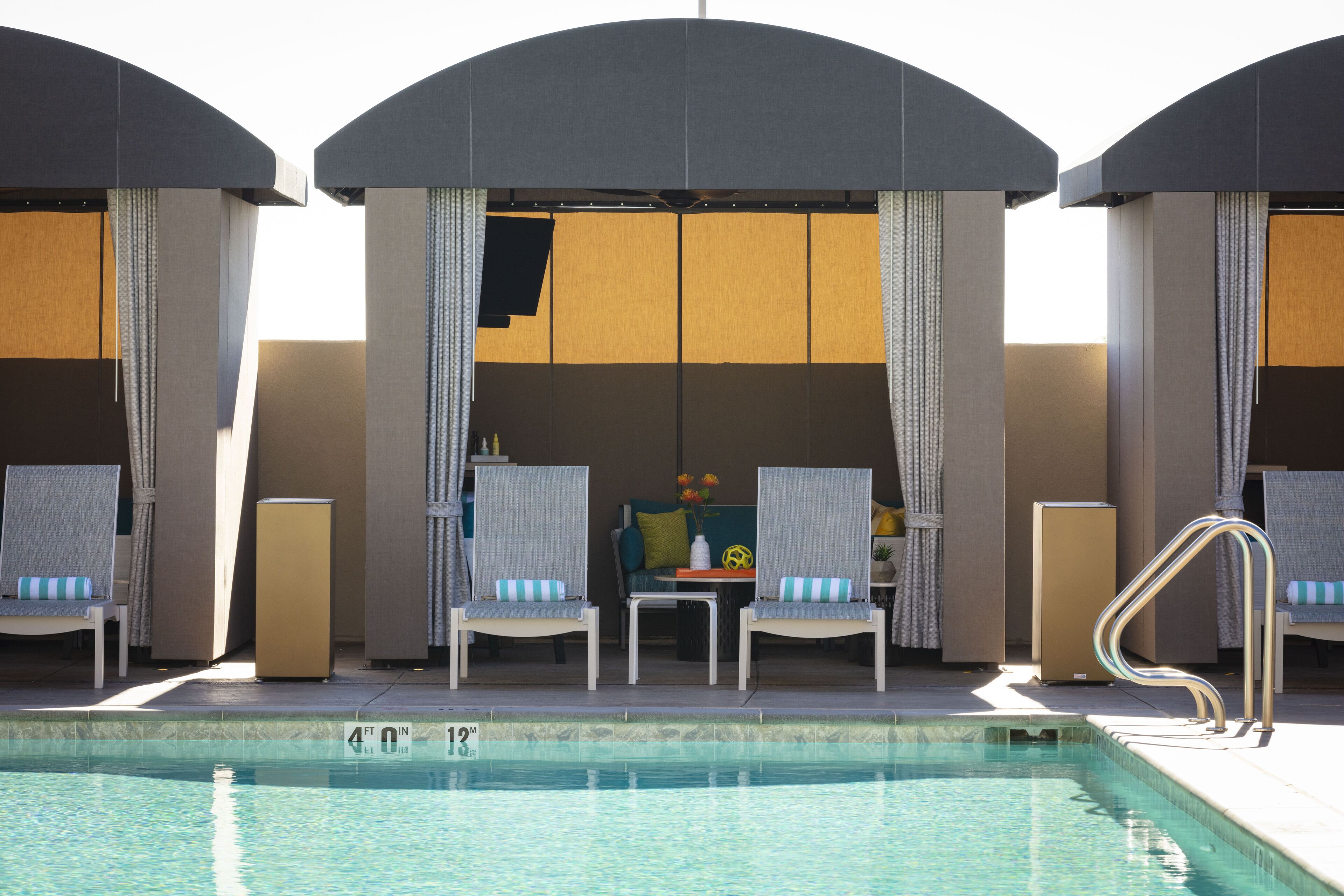 A poolside area with lounge chairs, a pool, and a sunshade structure.