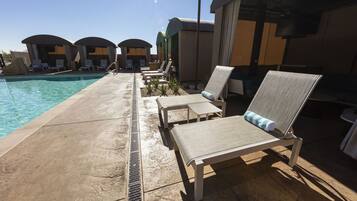 Un espace aménagé au bord de la piscine, comprenant des chaises longues, une piscine et un coin salon abrité.